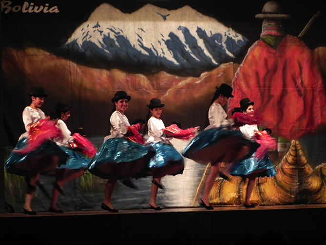 Junge Mädchen in bolivianischer Tracht mit Hut tanzen feurig