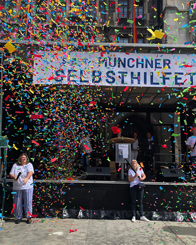 Münchner Selbsthilfetag 2022: Bunte Papierschnitzel werden als Zeichen der Vielfalt in den Himmel geblasen