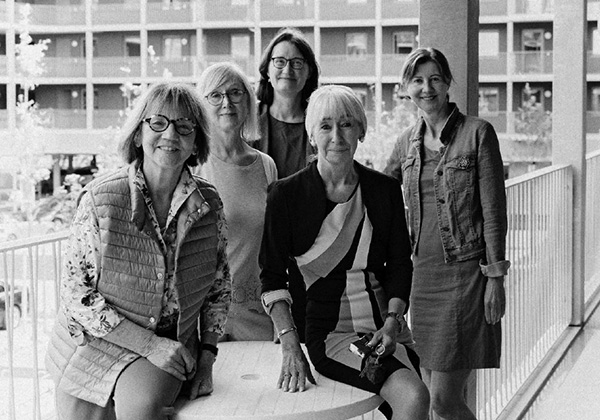 Schwarzweissfoto: Christa Lippmann mit Wohnfrauen von Wohngruppe 6 im Laubengang lachen in die Kamera