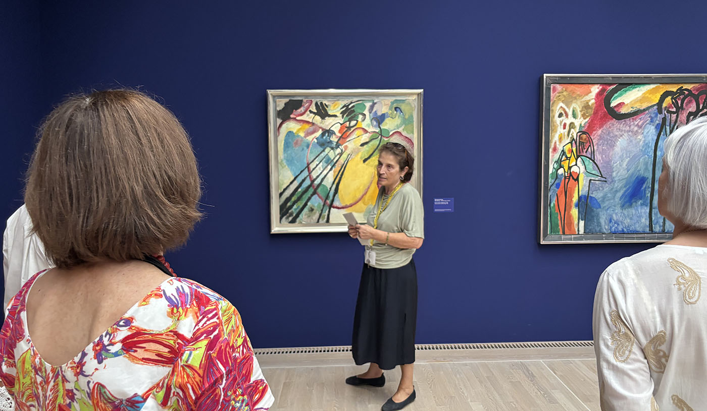Erklärungen zu Kandinsky vor einem seiner Werke auf dunkelblauer Wand